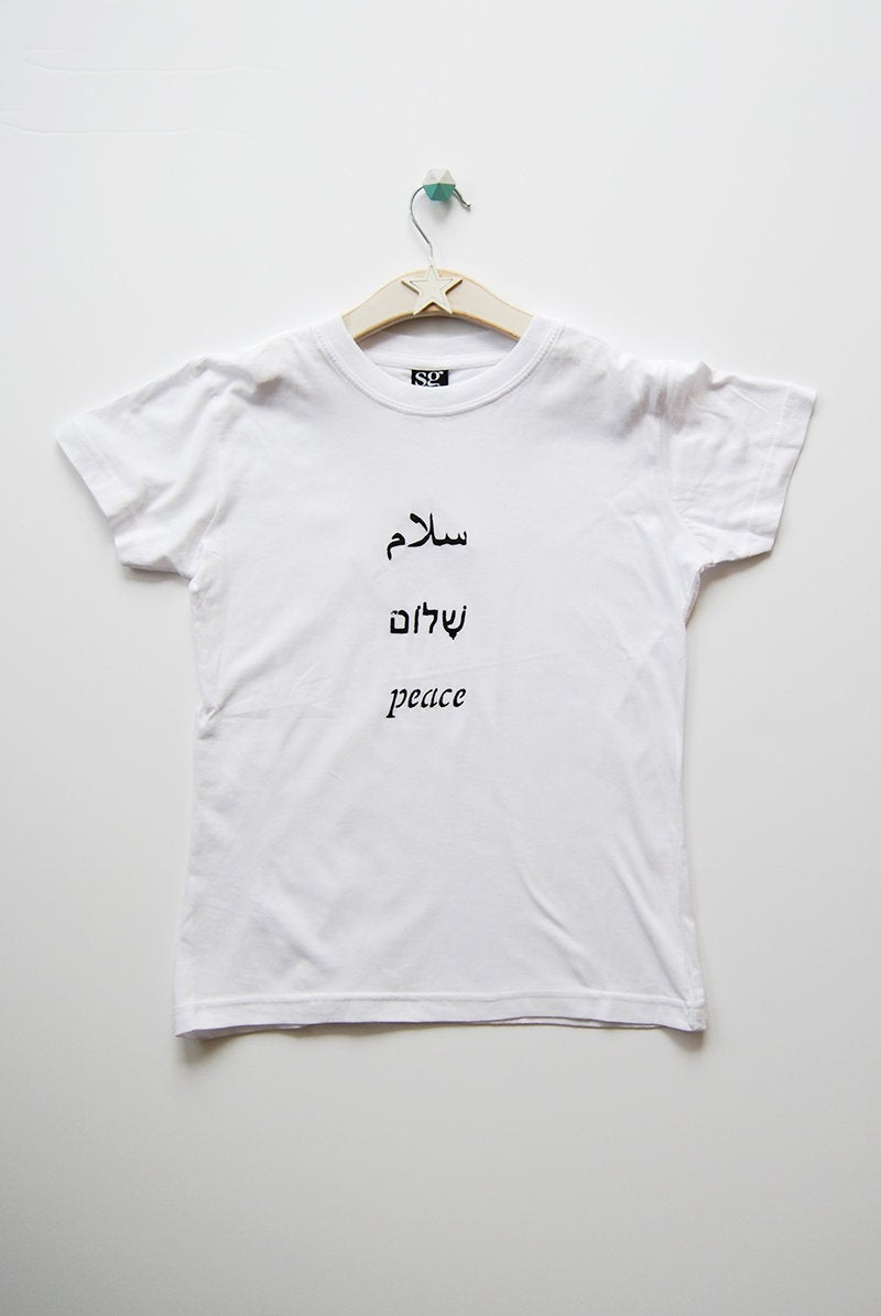 Salaam Shalom Peace in Arabic, Hebrew & English. White T-shirt with Black Writing. Simple and Minimal. Capsule Wardrobe.