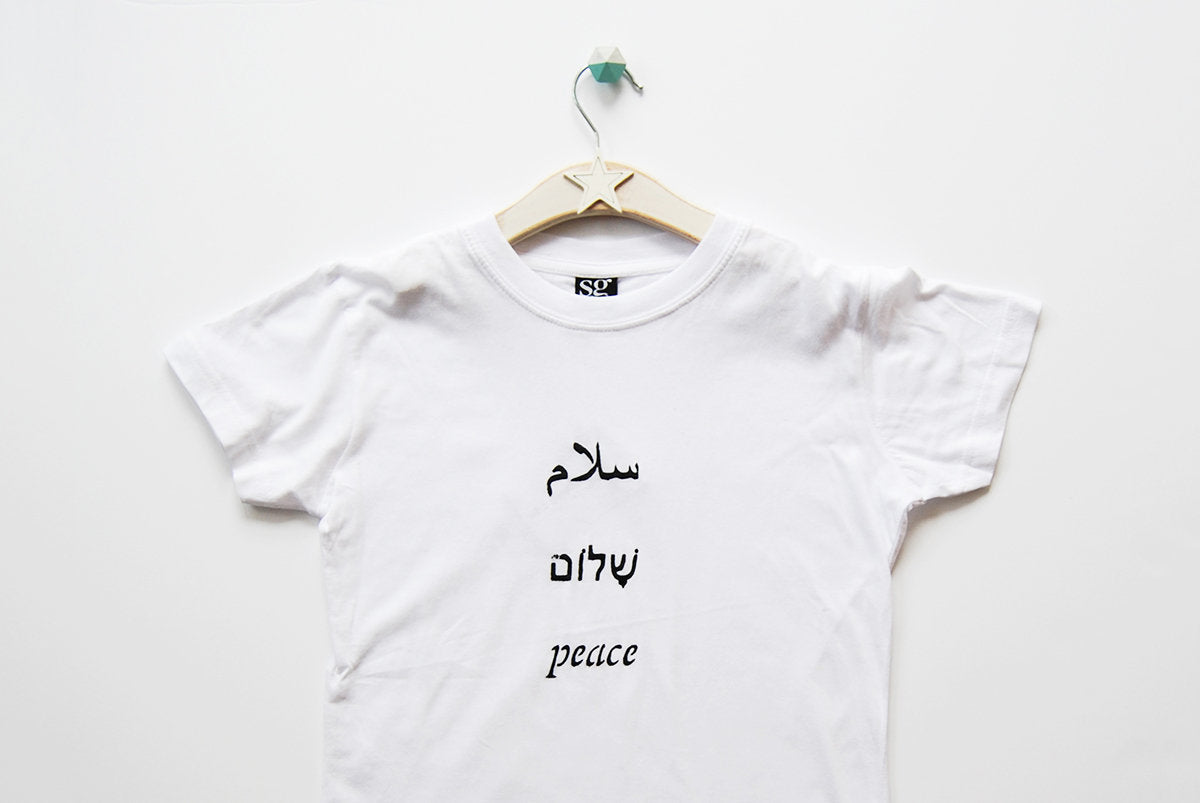 Salaam Shalom Peace in Arabic, Hebrew & English. White T-shirt with Black Writing. Simple and Minimal. Capsule Wardrobe.